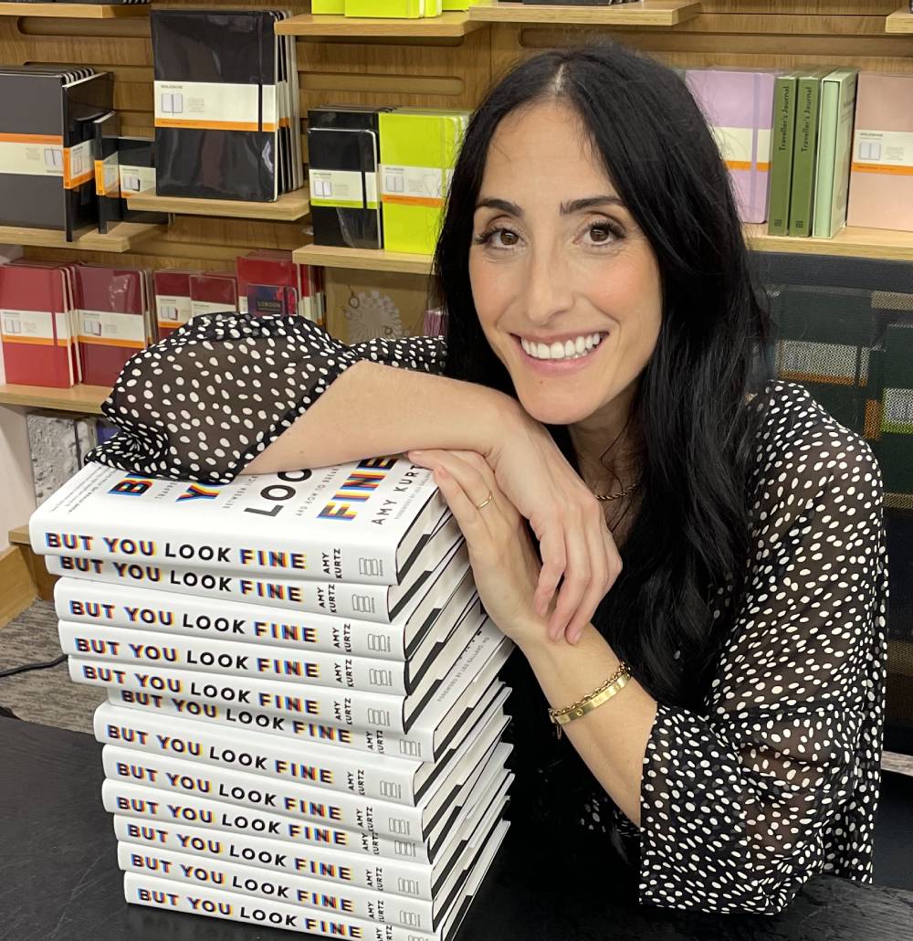 Amy Kurtz Leaning On a Stack of Her Books