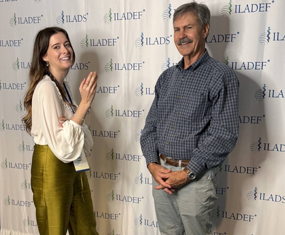 Tick Boot Camp at ILADS 2026: Official Podcast & Gala Emcees 21 Anna Roberts of Moresco PR and Dr. Bill Rawls at the ILADS conference backdrop.