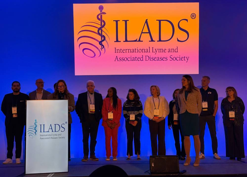 Tick Boot Camp at ILADS 2026: Official Podcast & Gala Emcees 9 Conference presenters gathered on stage beneath the ILADS logo.