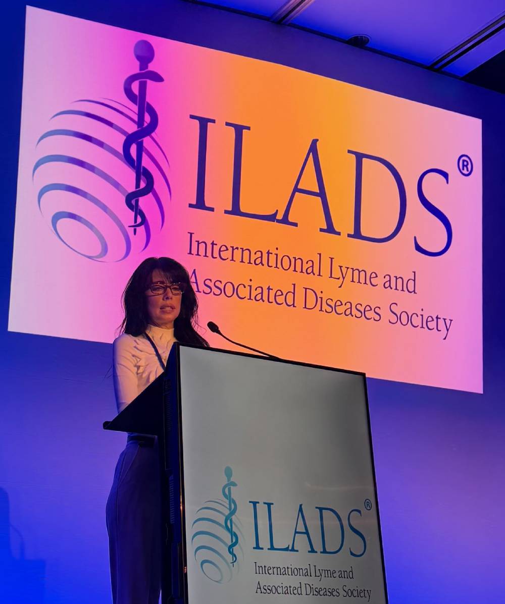 Tick Boot Camp at ILADS 2026: Official Podcast & Gala Emcees 10 Dr. Somer DelSignore presenting from the podium at the 2026 ILADS Scientific Conference.